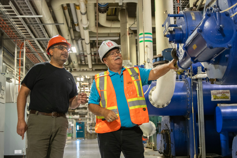 Two men having a conversation in front of industrial equipment