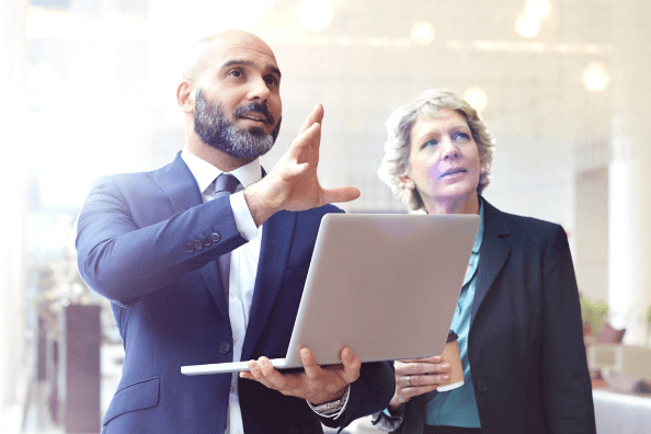 woman and man having a discussion while man holding laptop