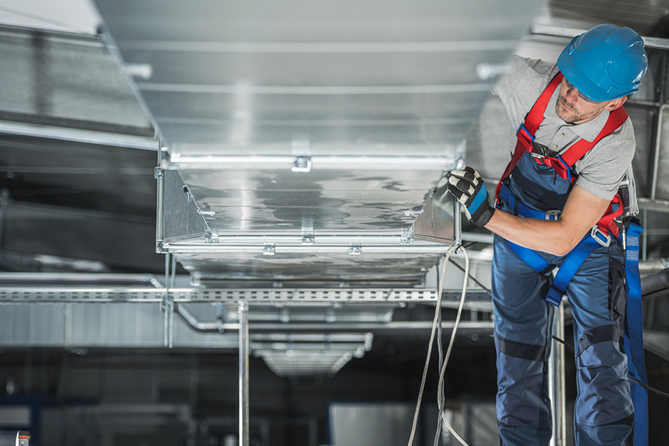 technician working on ventilation within a commercial building