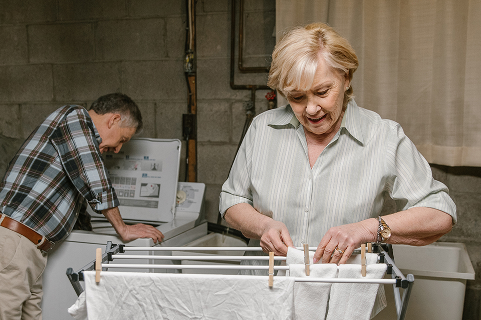 Retired couple doing laundry by hanging washed load onto a drying rack