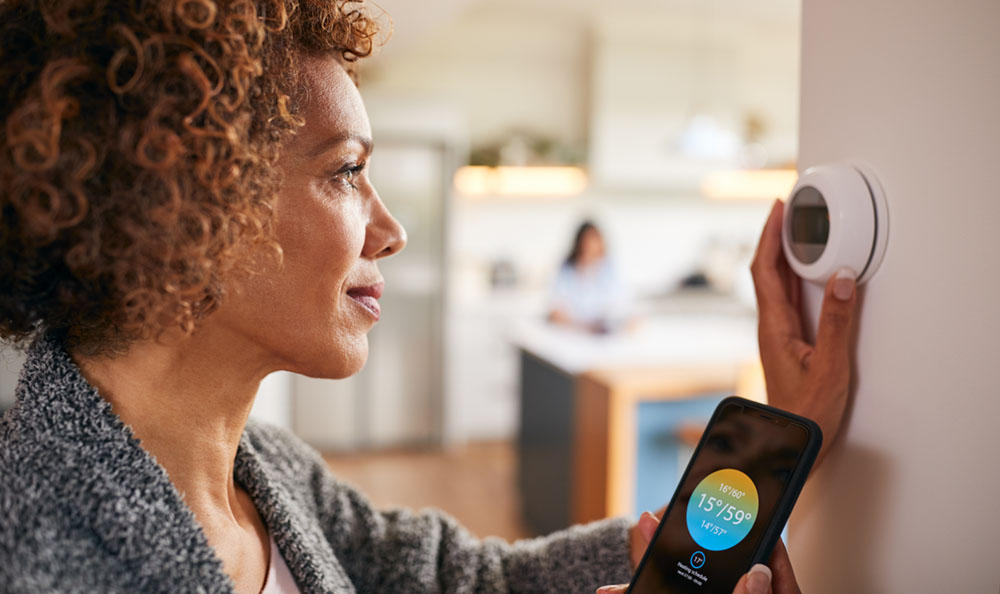 woman adjusting smart thermostat in her home